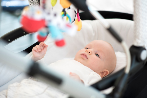 baby in pram looking at toy