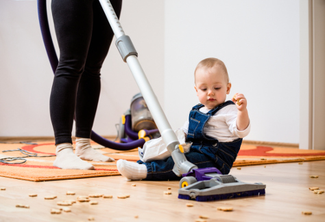Mum hoovering while baby on the floor
