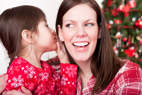 Child whispering to mum at christmas