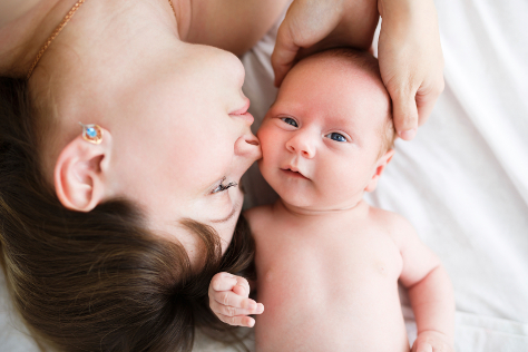 Mum laying down kissing newborn