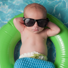 baby in sunglasses on rubber ring in pool