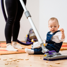 Mum hoovering while baby on the floor