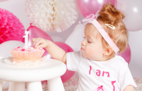 One year old girl eating her birthday cake