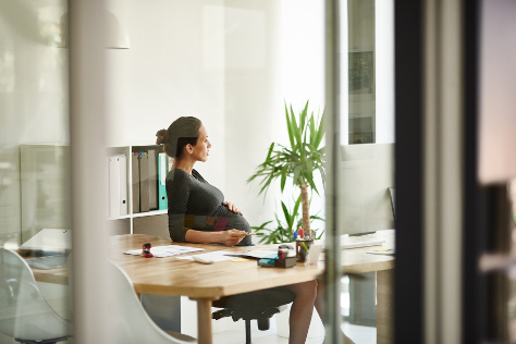 Pregnant woman sat at work desk