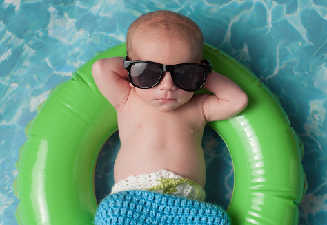 baby in sunglasses on rubber ring in pool