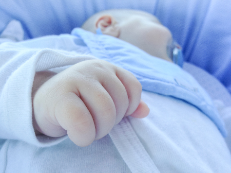 Baby asleep in travel cot