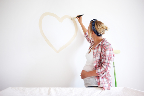 Pregnant woman painting wall